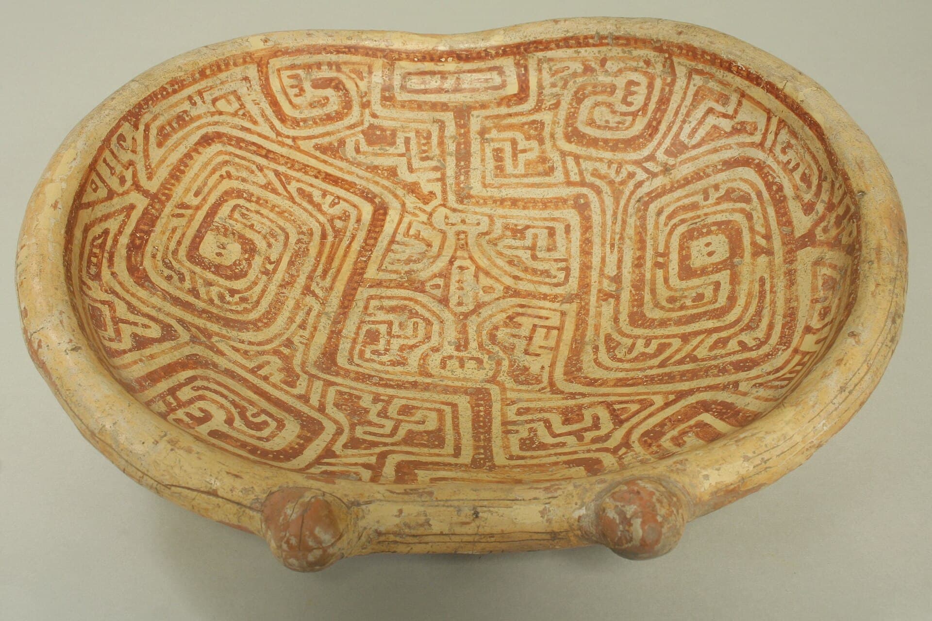 Marajoara-Keramikteller mit rot-cremefarbenen Labyrinth- und Spiralmustern und einem Gesicht in der Mitte